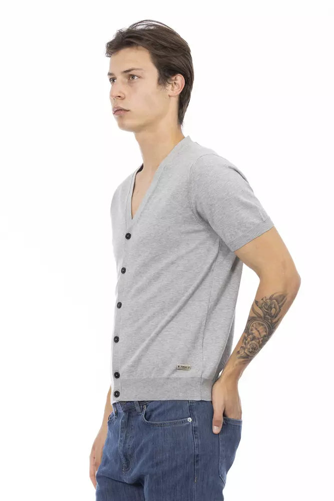 Man wearing gray sweater vest over blue jeans