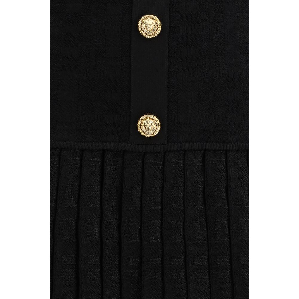 A black cocktail dress with a gold button detail on the front