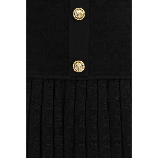 A black cocktail dress with a gold button detail on the front
