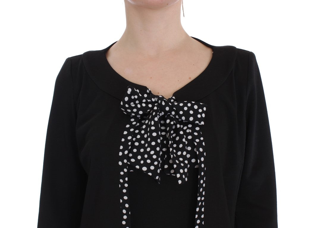 A black dress with a bow on the front, worn by a person