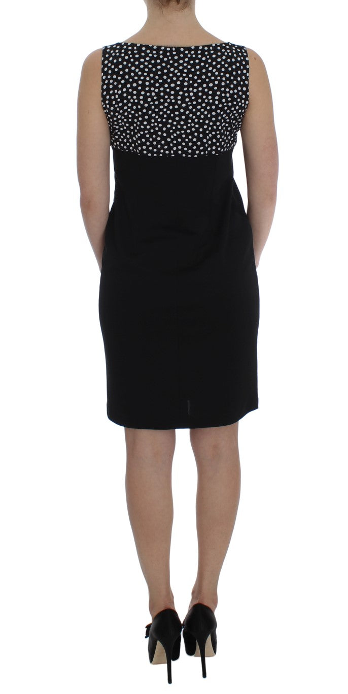 A black dress with a white polka dot pattern on the bodice, paired with a matching sweater