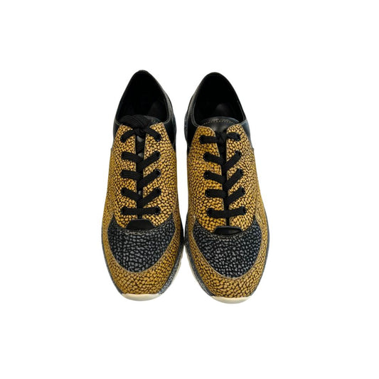 Pair of women's sneakers with gold laces, beige leather upper and black sole