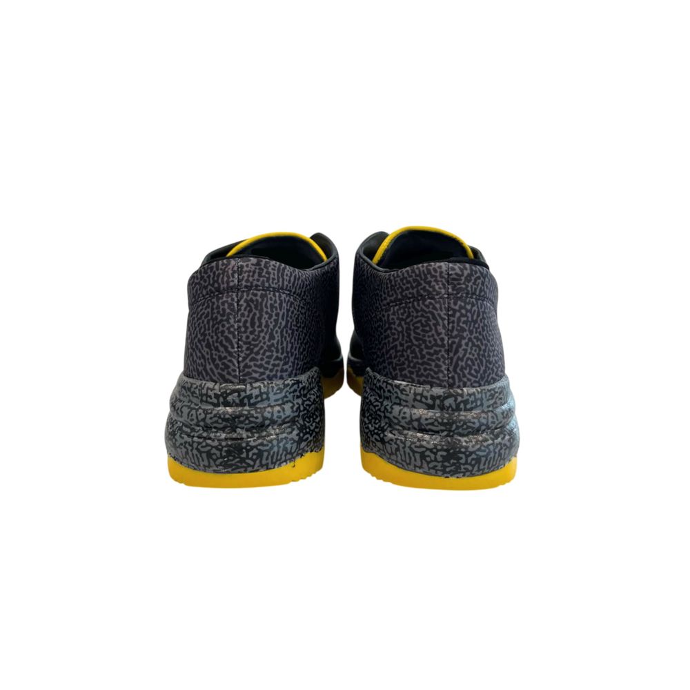 Pair of black leather women's sneakers with yellow accents, featuring a textured pattern and lace-up closure