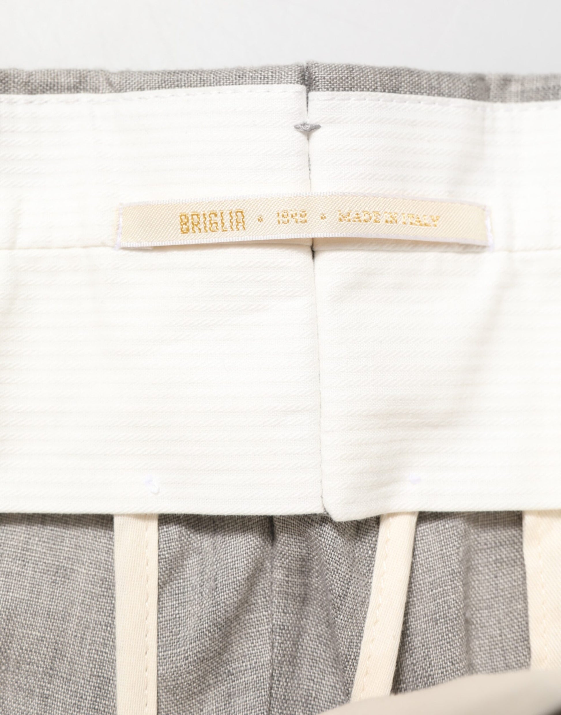 A pair of gray mid-waist dress pants with a label that reads "Briglia 1949"