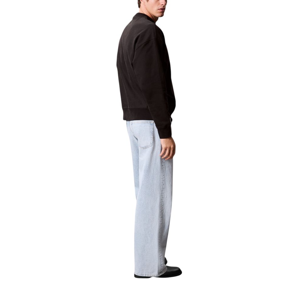 Man wearing black jacket and blue jeans standing against white background