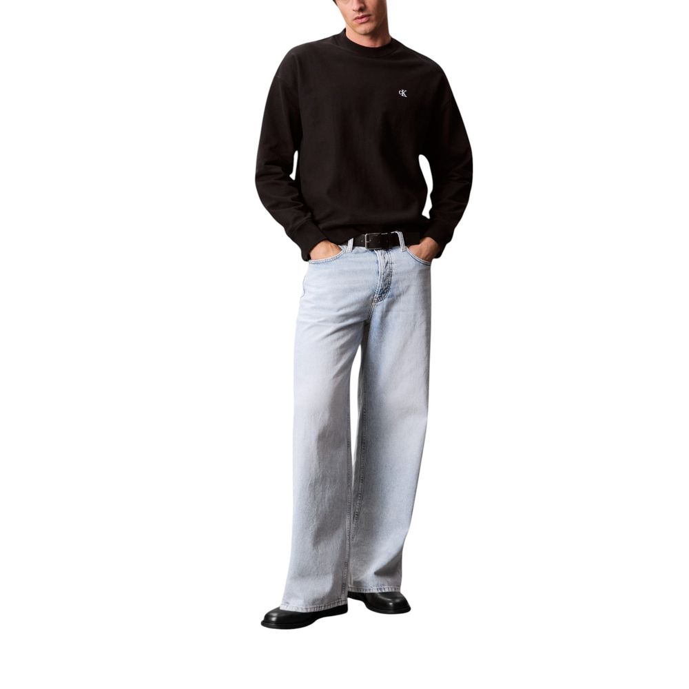 Man wearing black sweatshirt and blue jeans
