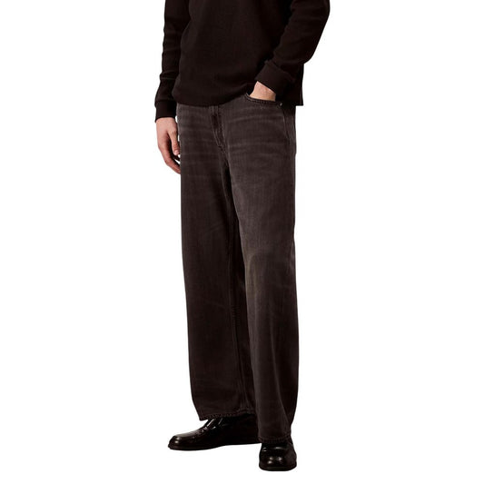 Man wearing black sweater and brown pants standing against white background