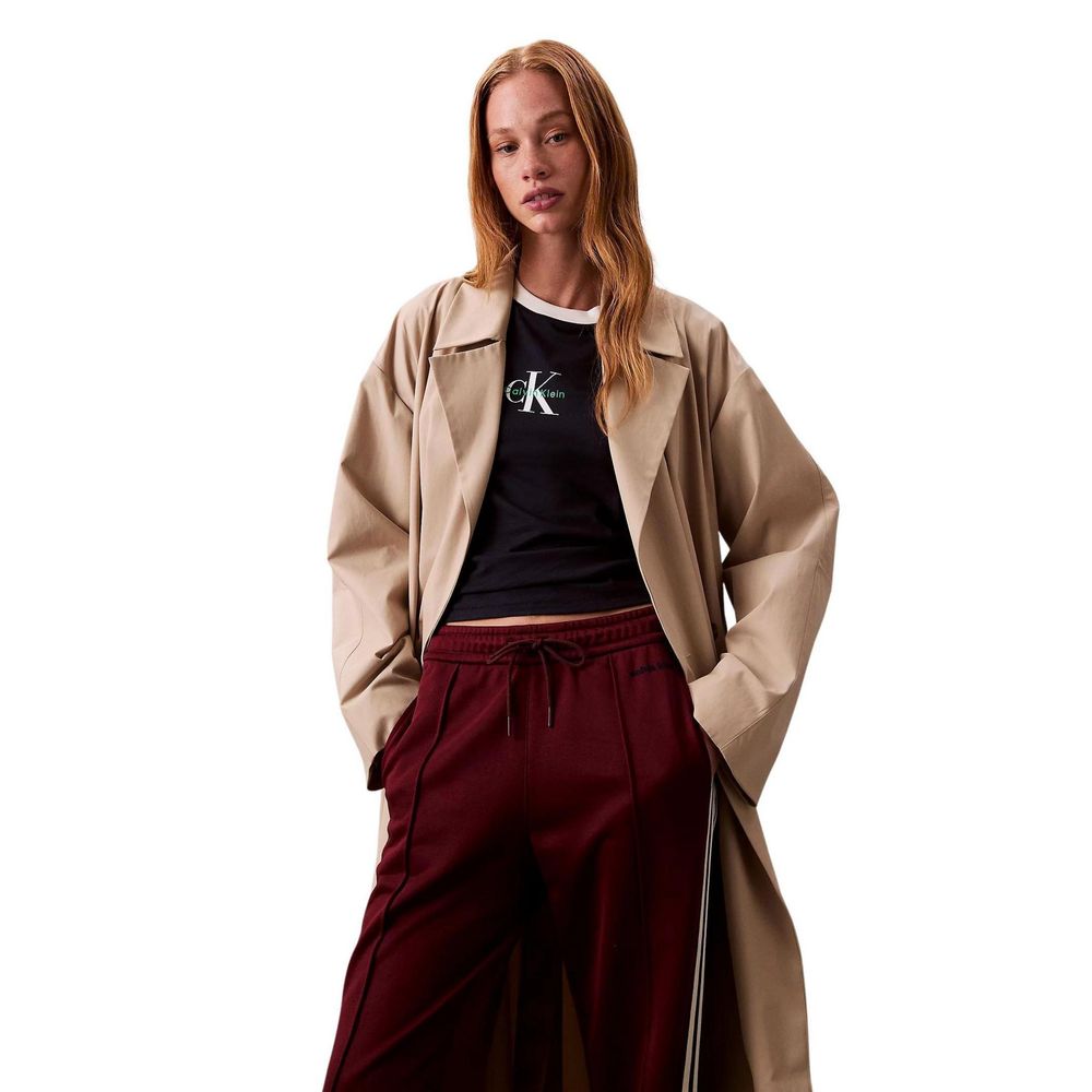 Woman wearing a tan trench coat over maroon pants