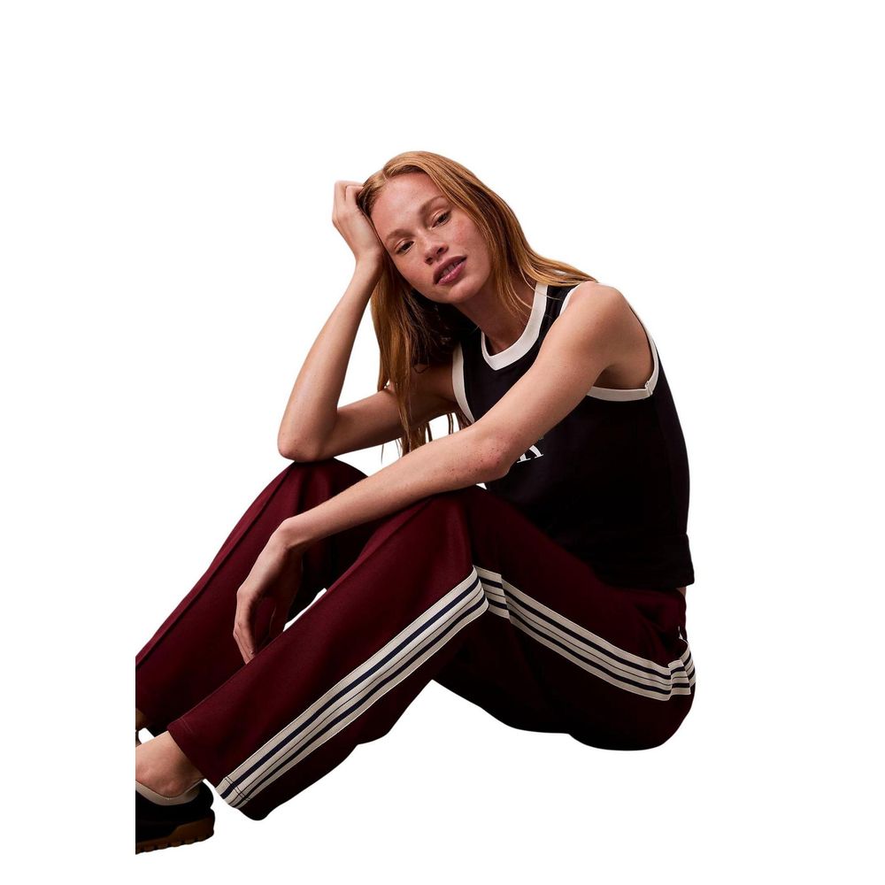 Woman wearing maroon track pants with white stripes