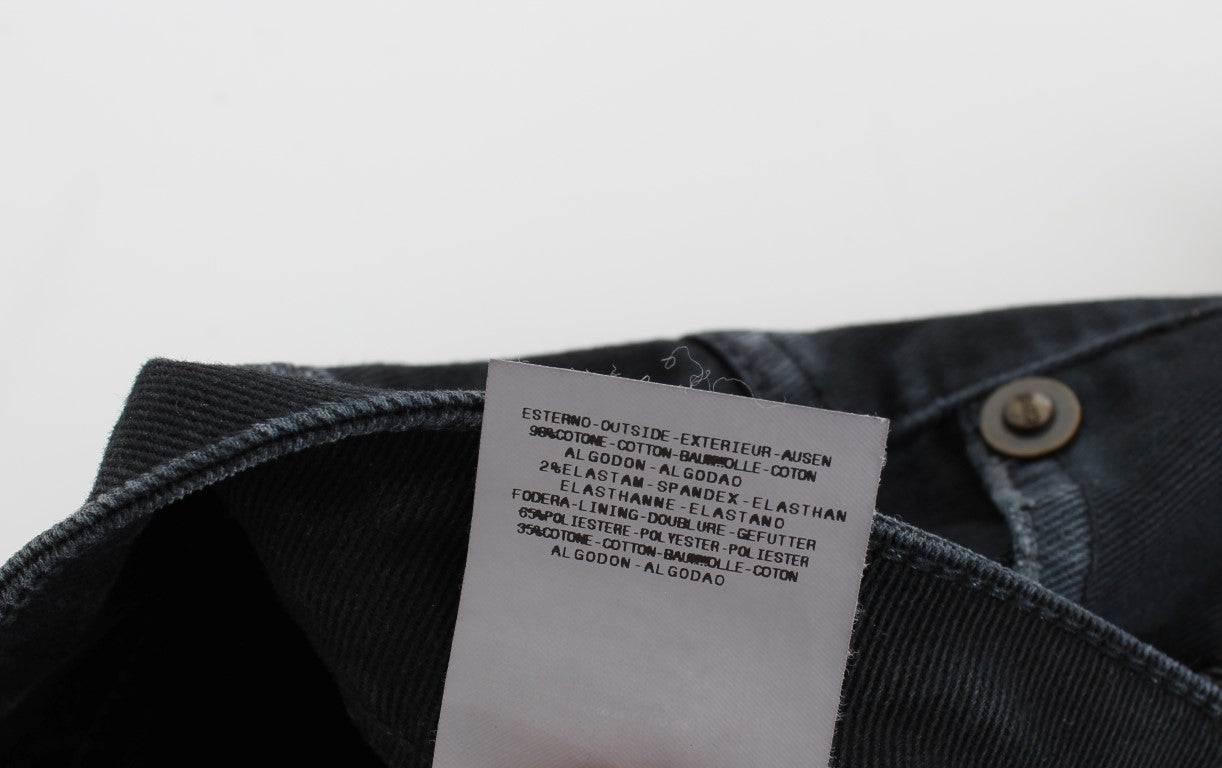 A pair of jeans with a tag attached to the waistband. The tag contains text that is too small to read clearly in this des