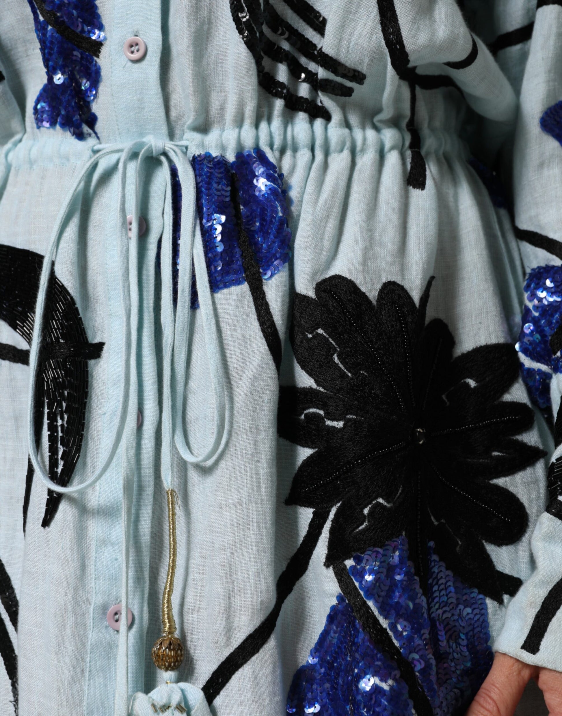 A long blue dress with sequin embellishments and a tie at the waist