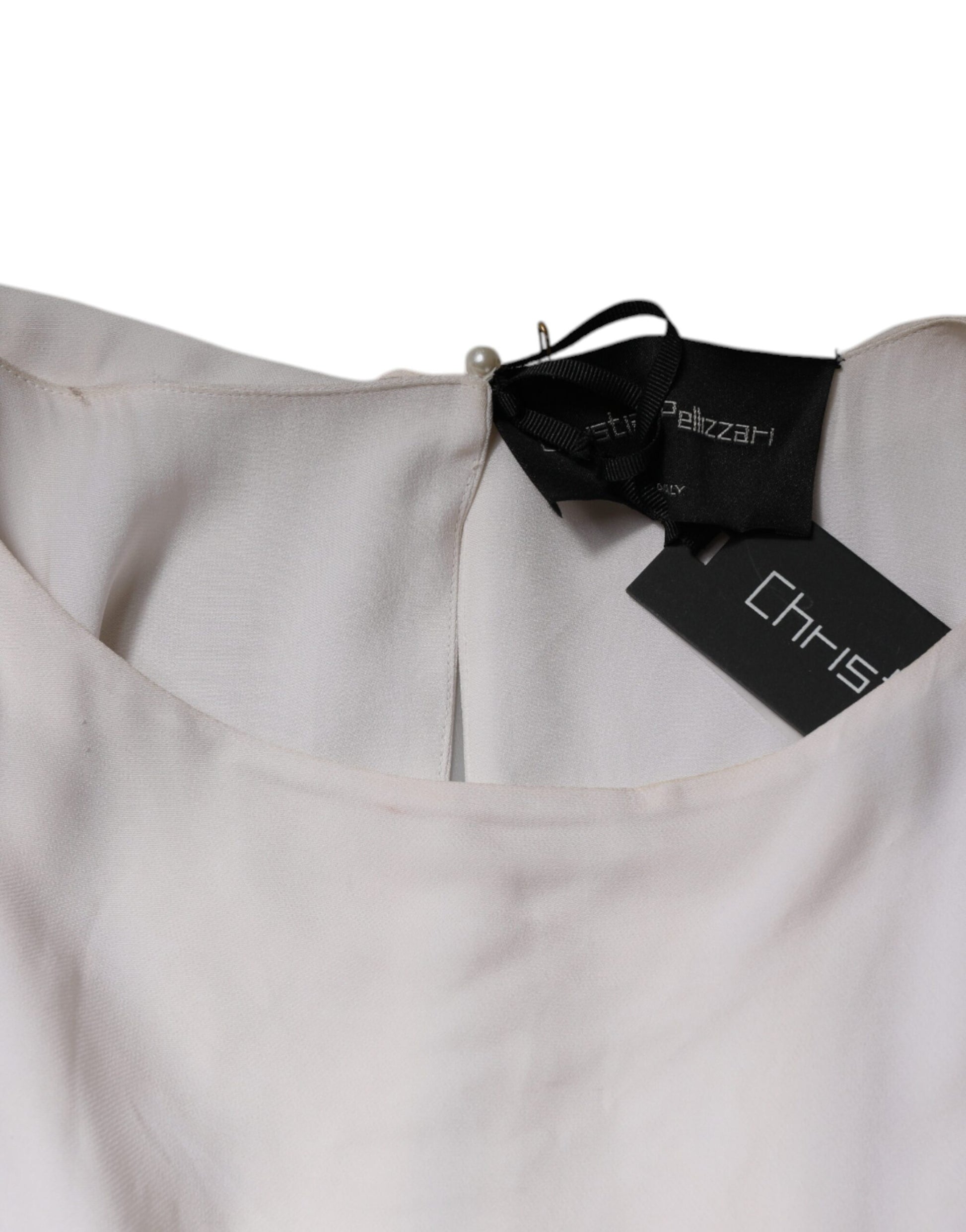 A long off-white dress with embellishments, featuring a high neckline and a tag that reads "Christian Pellizzari"