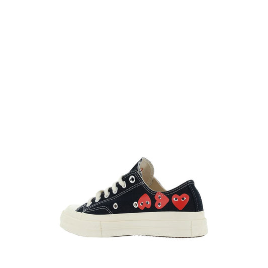 A pair of black canvas low top sneakers with a heart pattern on the side, featuring the branding of Comme des Garçons Play an