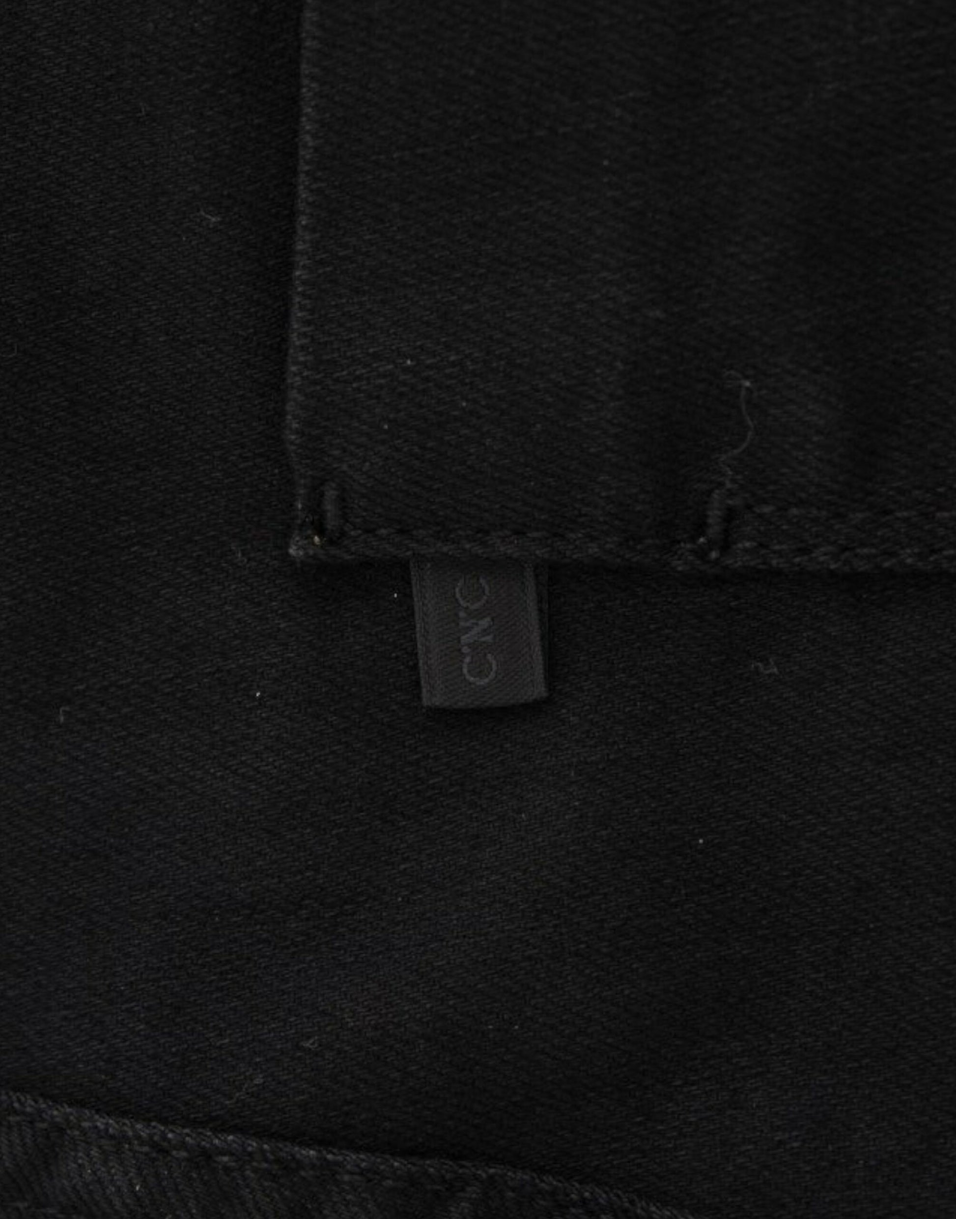 A close-up of a garment with visible stitching and a tag attached to it. The tag has text on it, but the specific details