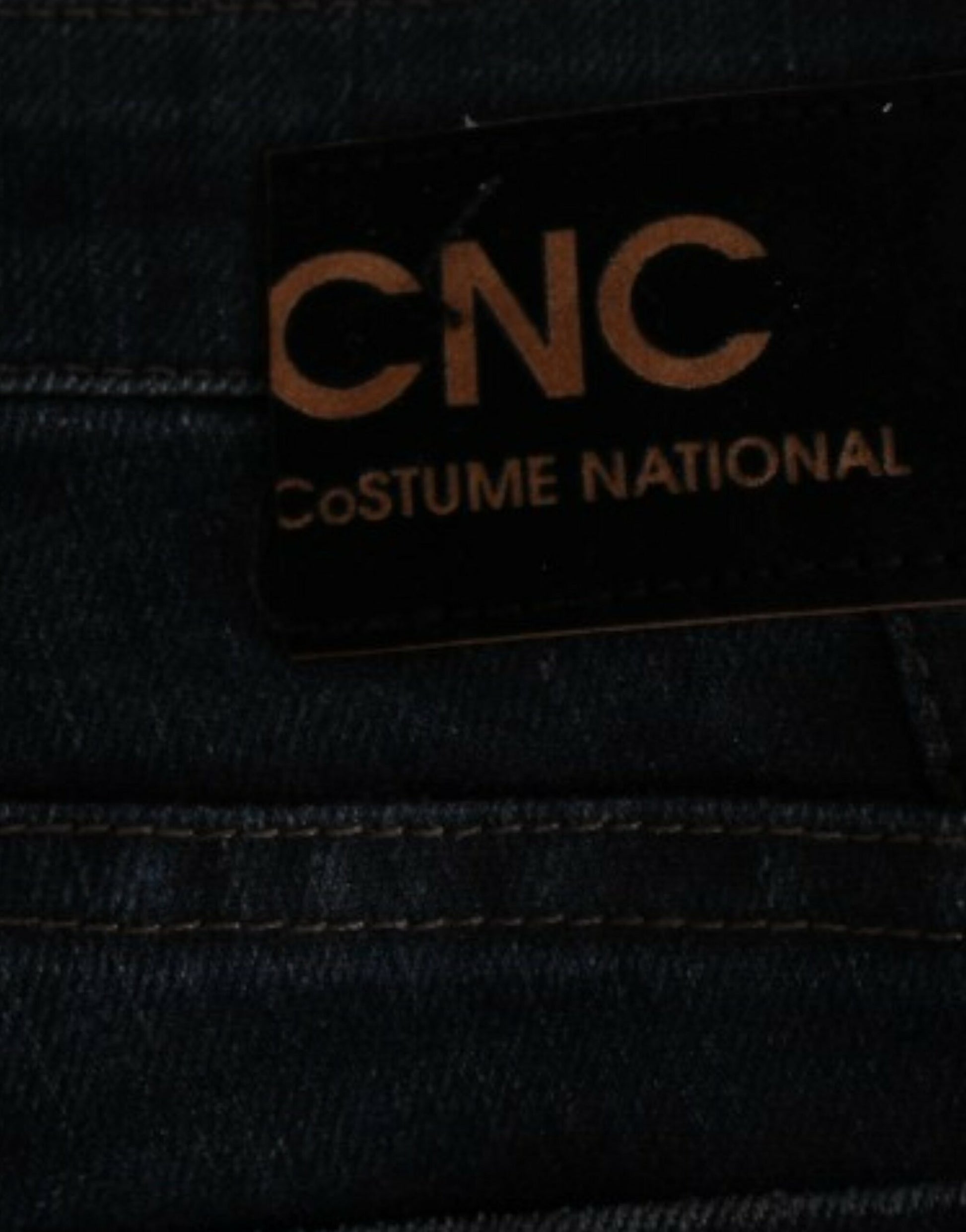 A close-up of a denim jeans label with the text CINO COSTUME NATIONAL visible on it