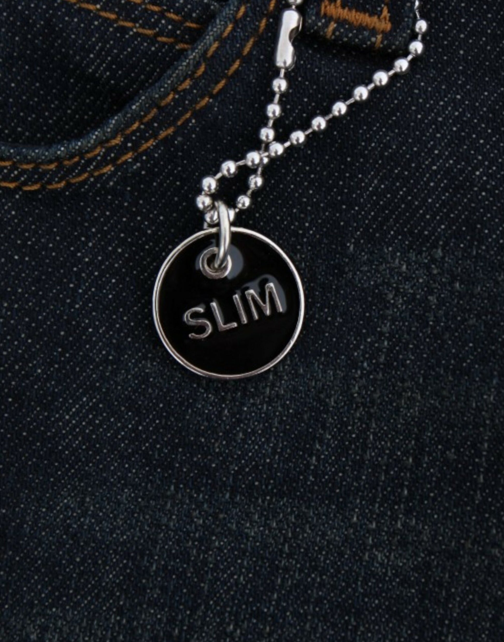 Silver chain with a black tag that says SLIM attached to a pair of jeans