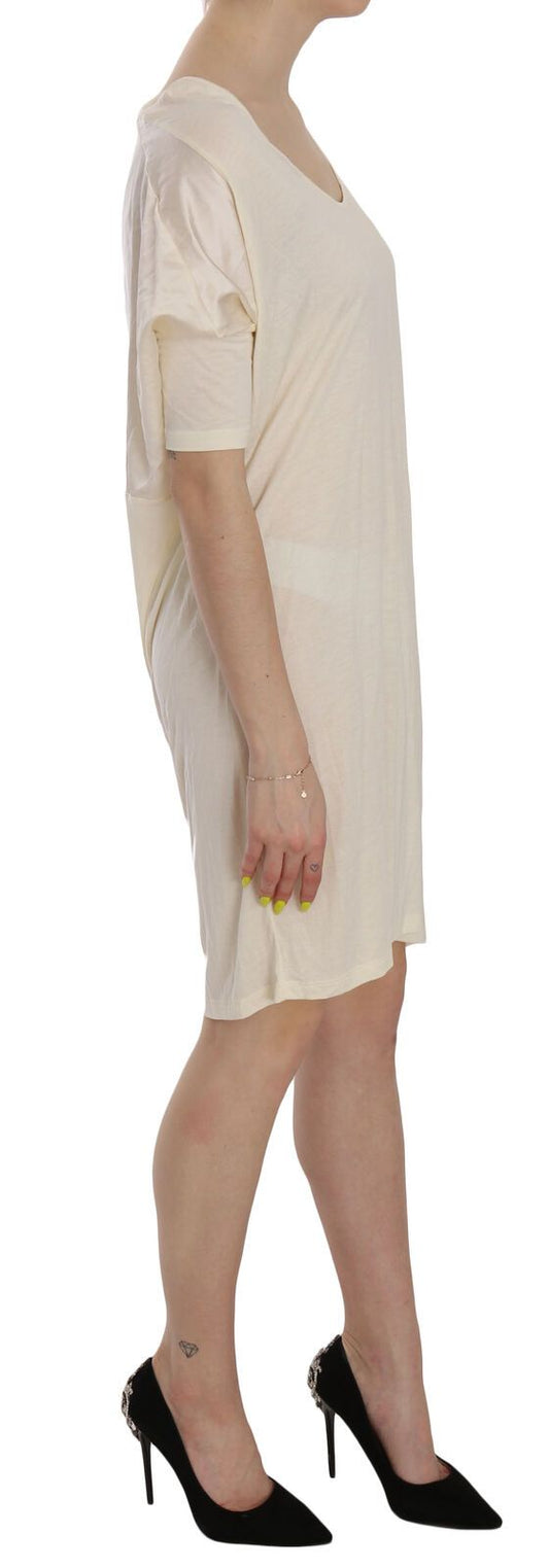 A knee length dress with a round neckline, cream color, and visible detailing on the bodice
