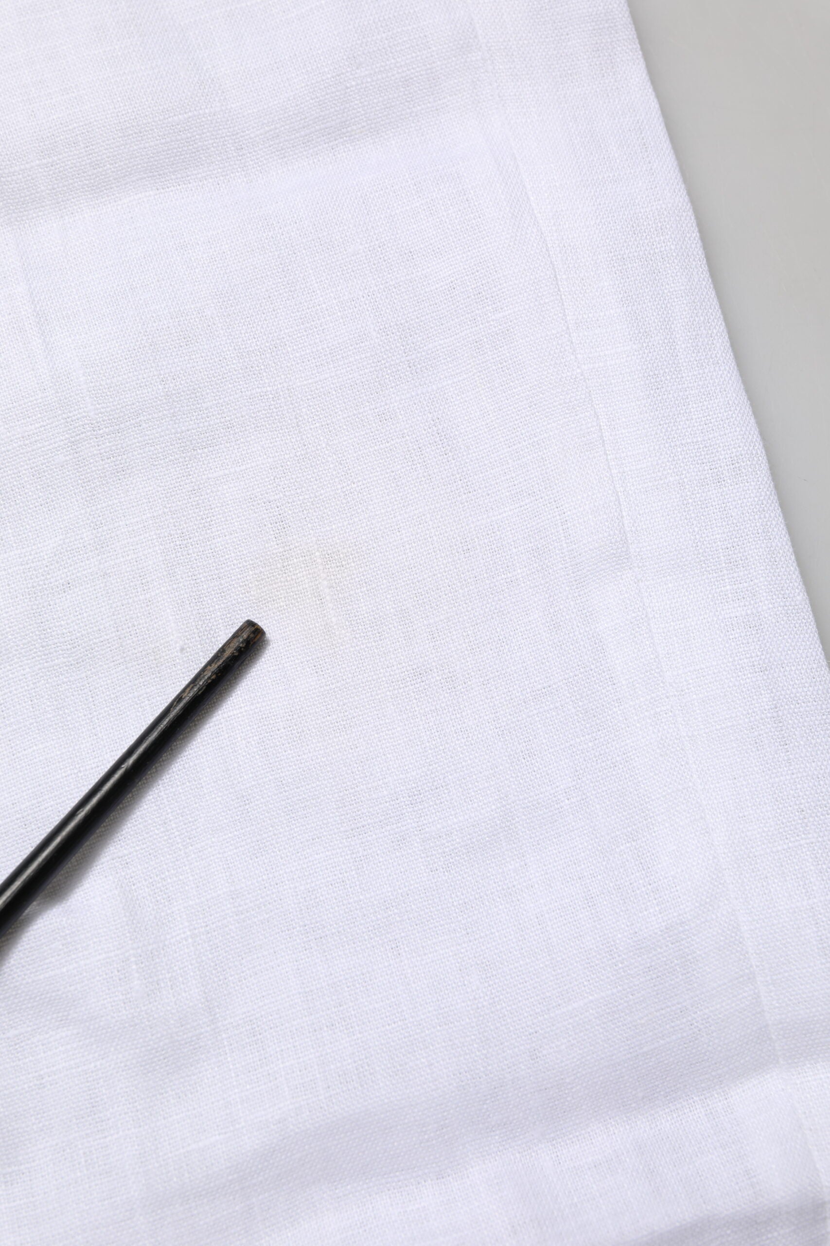 A pair of white linen formal dress trousers with a black button