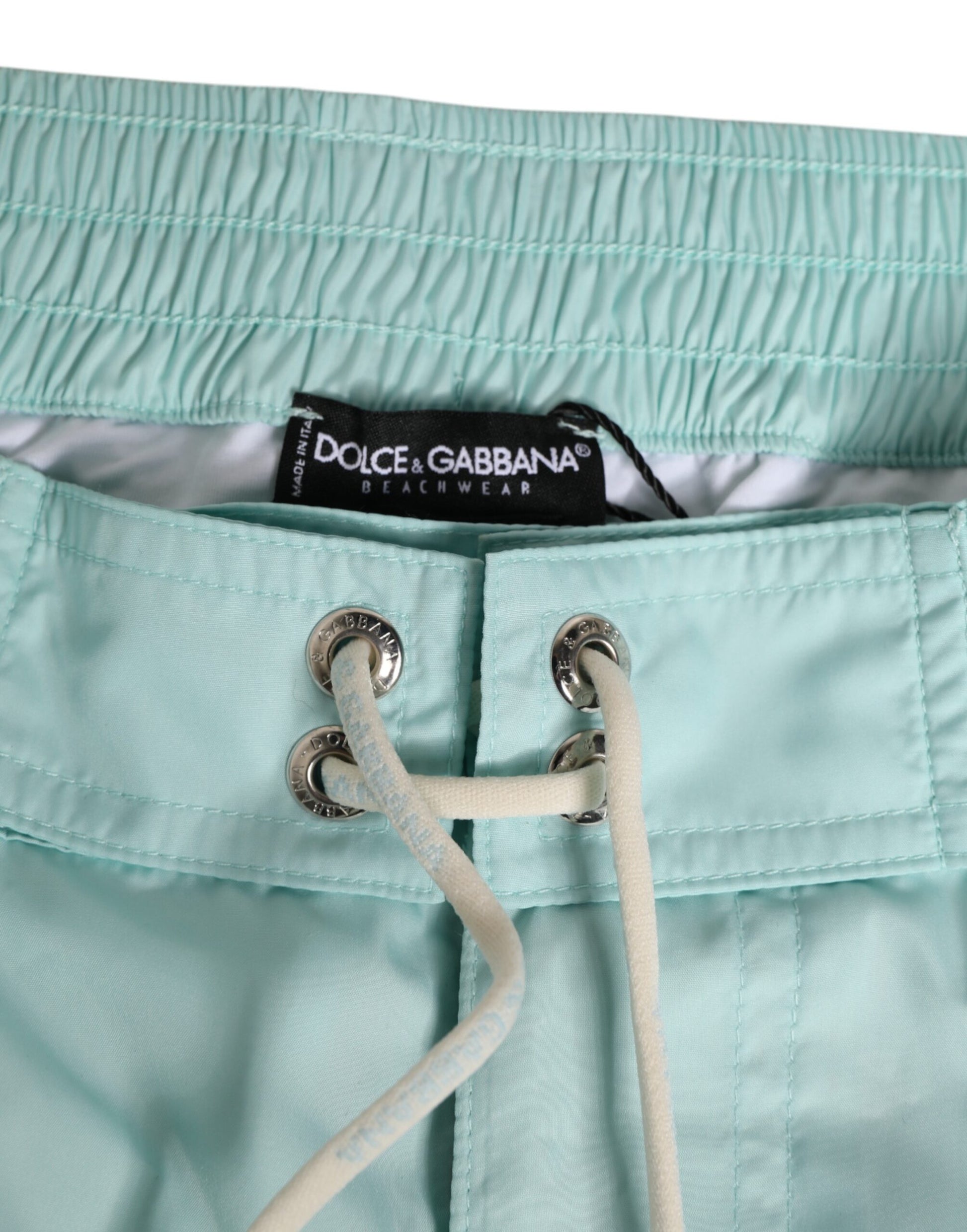 Light blue swim trunks with white trim and a black label on the waistband