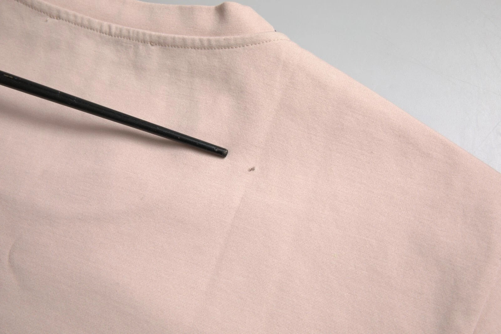 Pink shirt with black pen marking on sleeve
