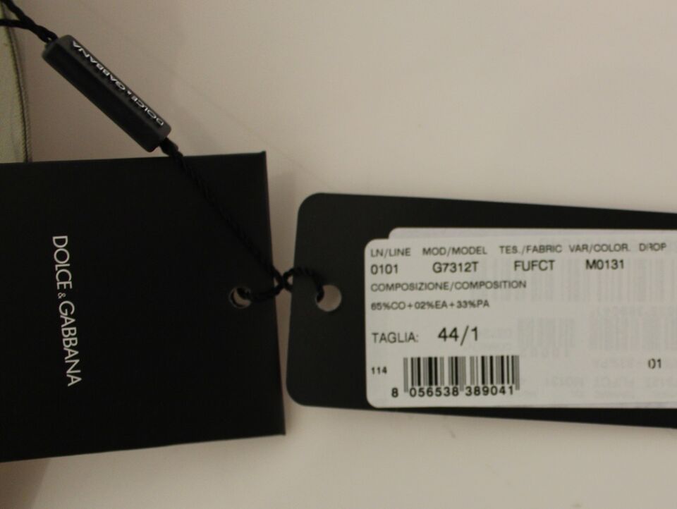 A black tag with white text on a beige cotton dress vest blazer jacket