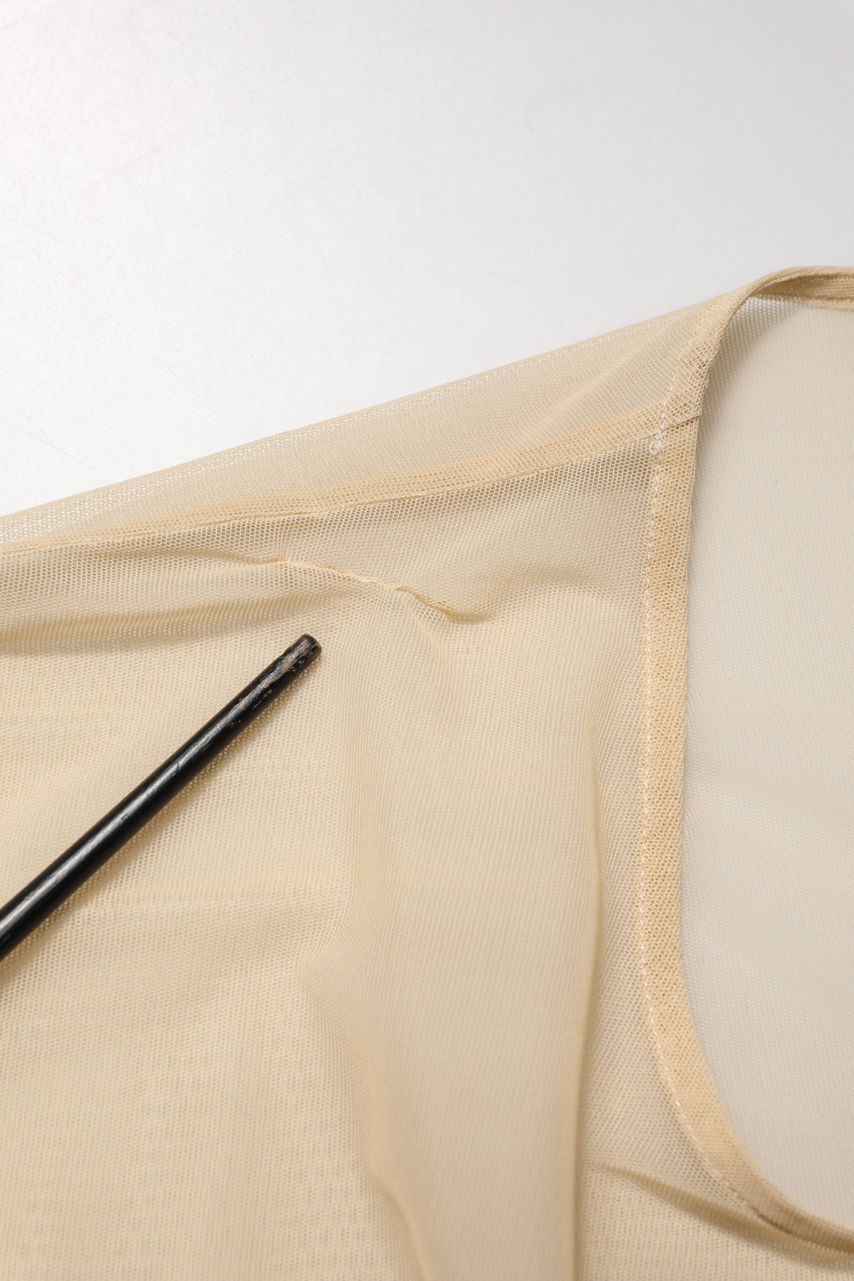 Tan tank top with black stitching on white background
