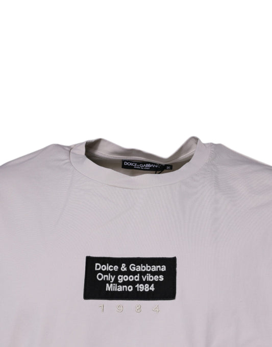 The shirt is beige with a black logo on the front