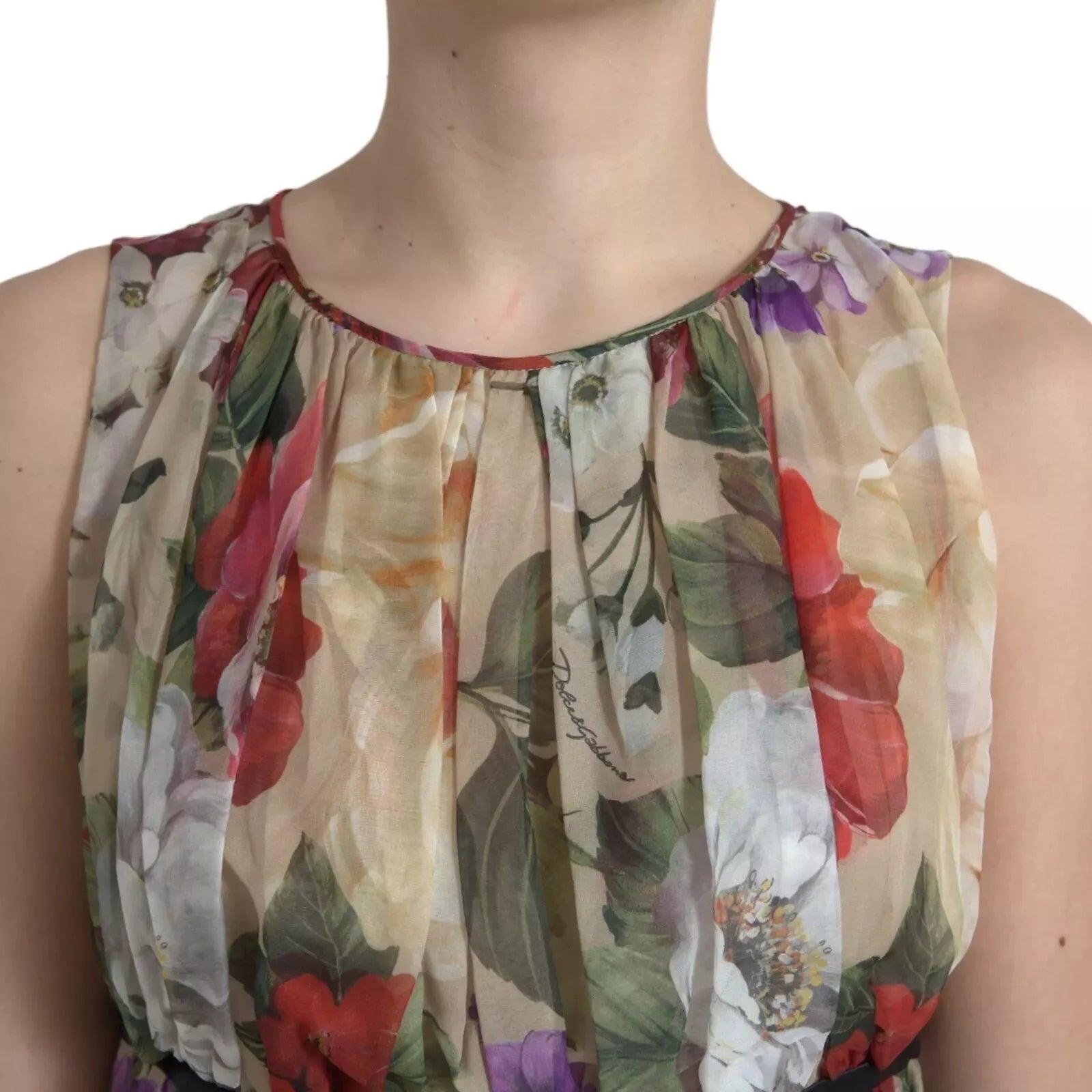 A sleeveless, beige floral dress with an A-line silhouette. It features a vibrant flower pattern and is desig