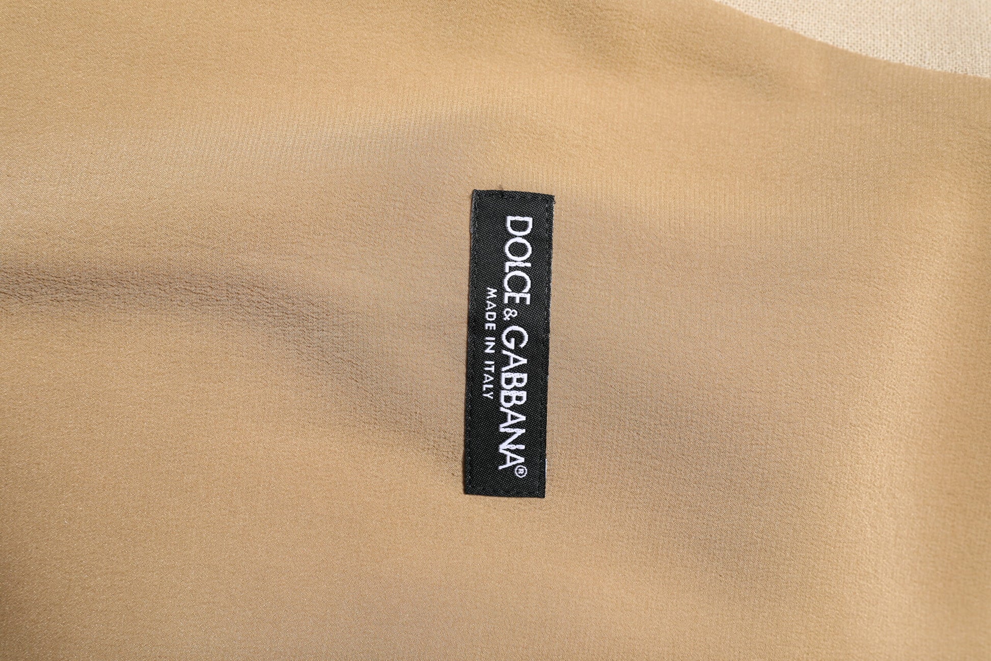 A beige linen dress shirt with a label that reads "Dolce & Gabbana" on the front