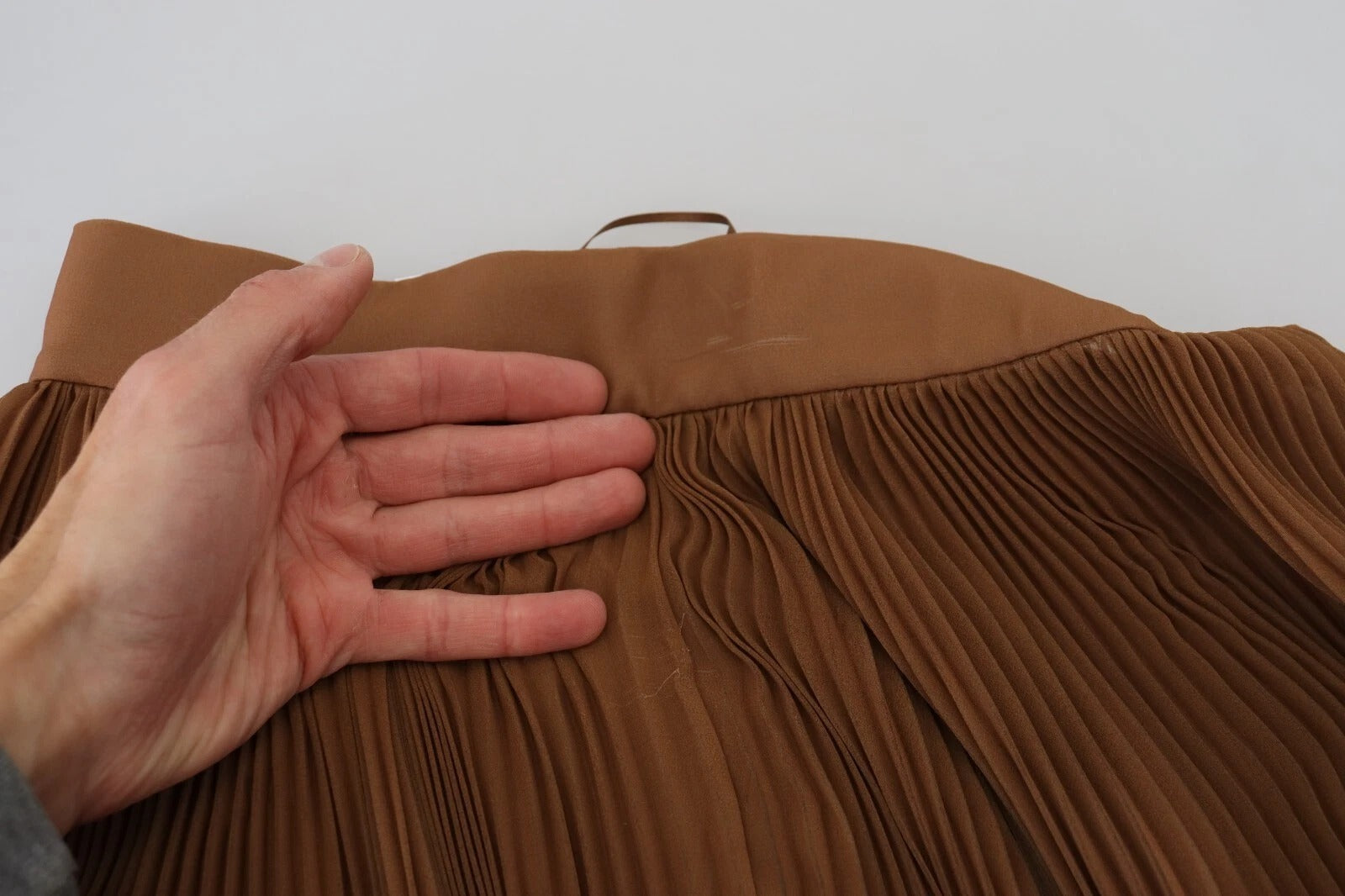 Hand holding a brown leather skirt