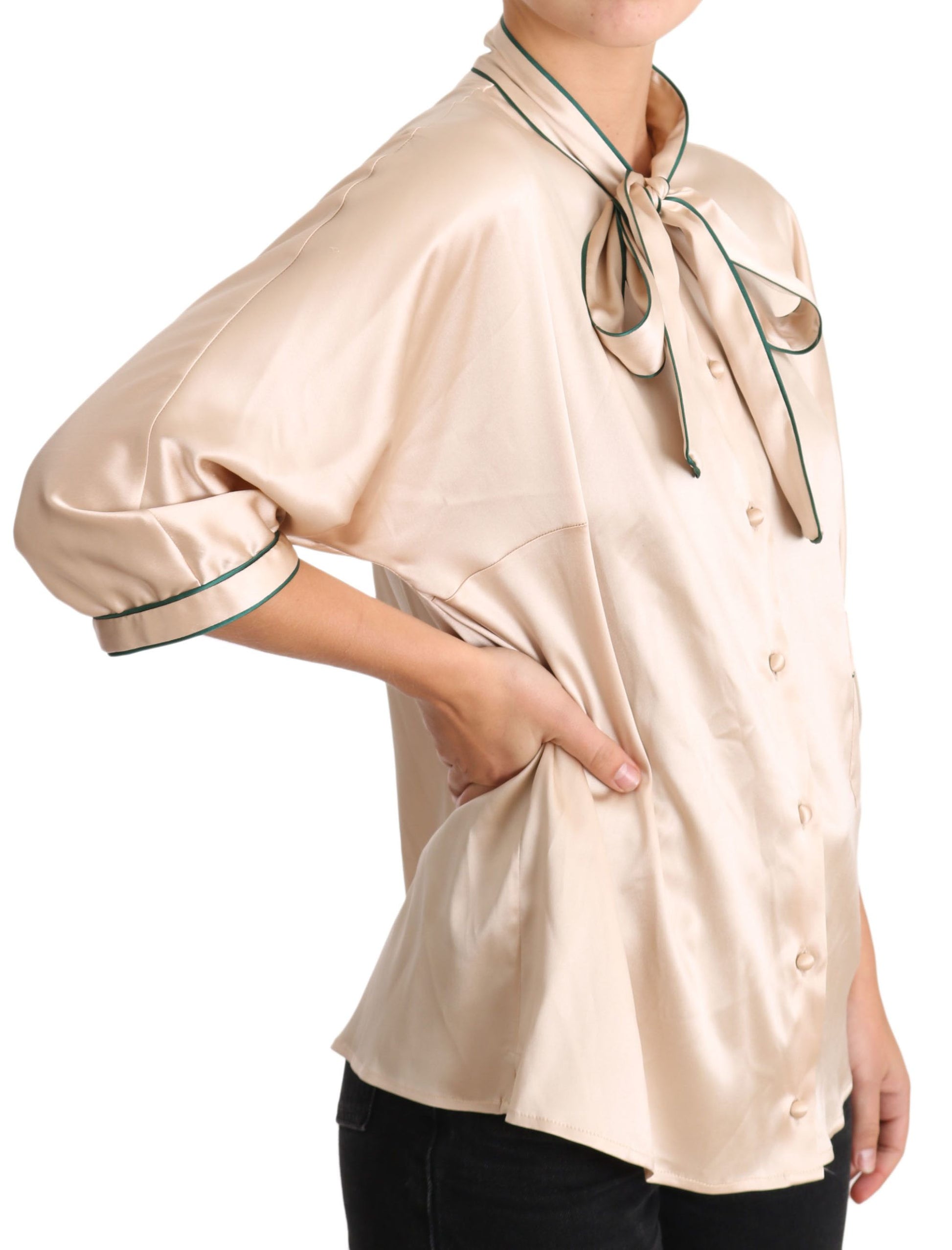 The shirt is beige with a bow tie on the front