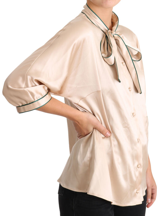 The shirt is beige with a bow tie on the front