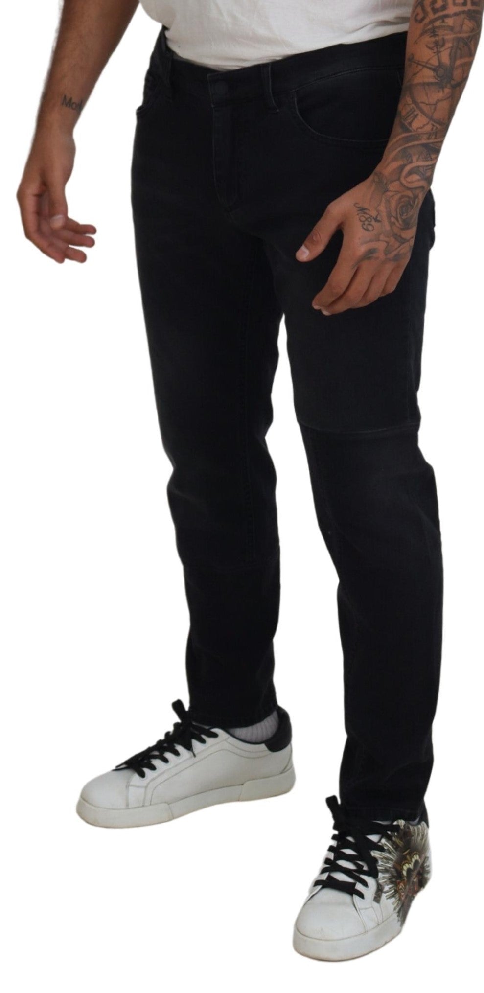 Man wearing black pants, white shirt, tattoos on arms, sneakers