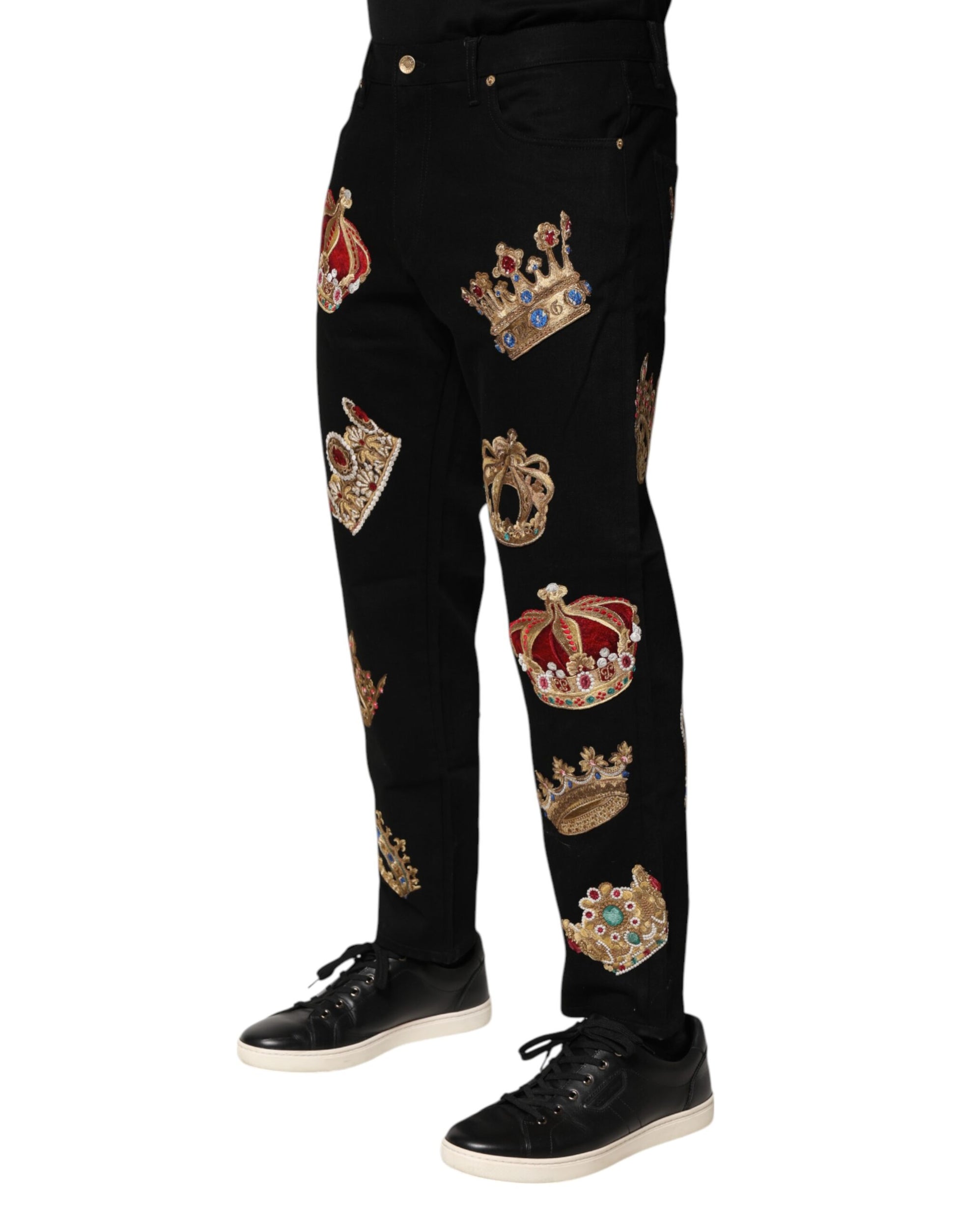 A pair of black trousers with gold embroidery featuring crowns and other royal symbols