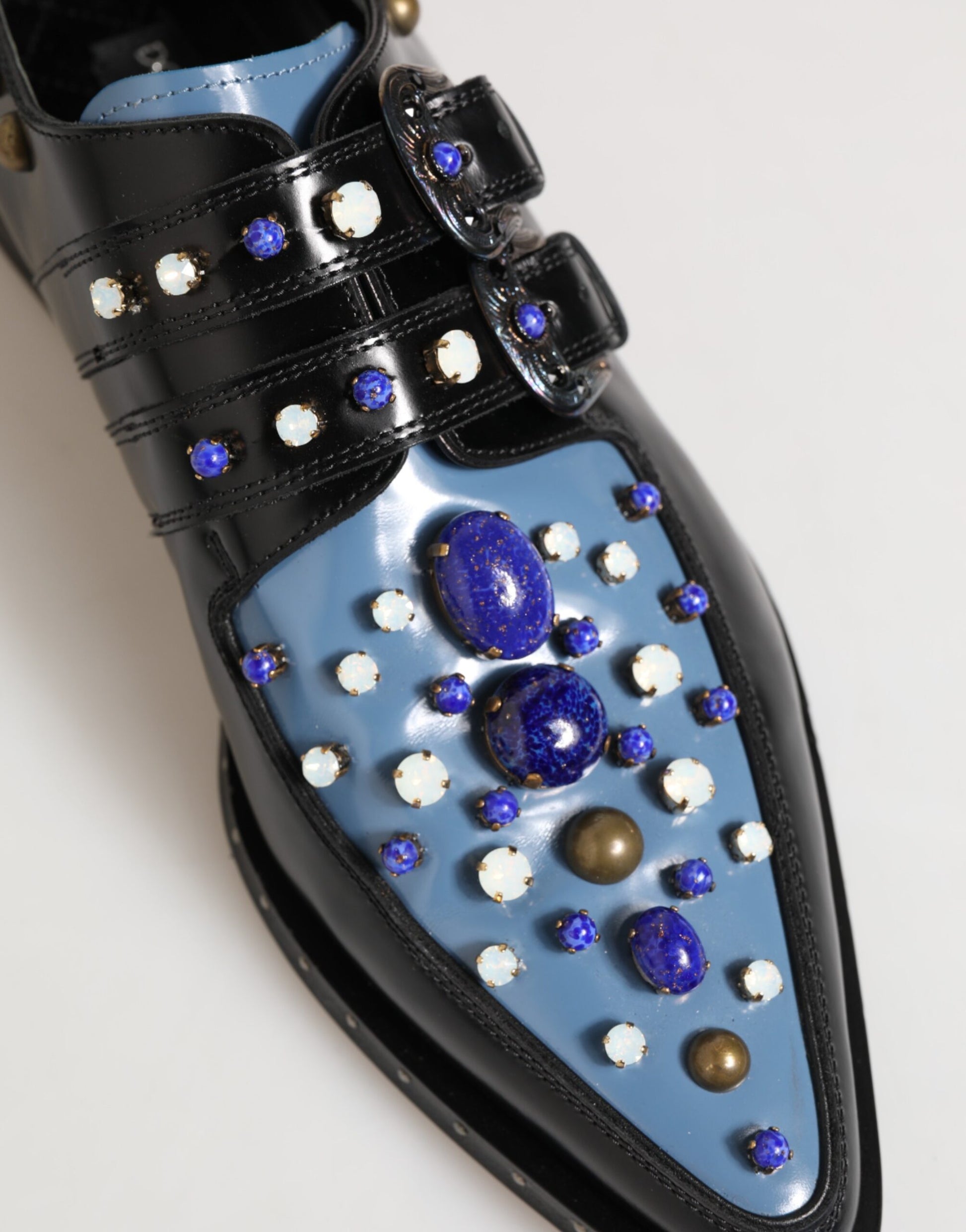 A pair of blue embellished monkstrap dress shoes with black straps and gold accents