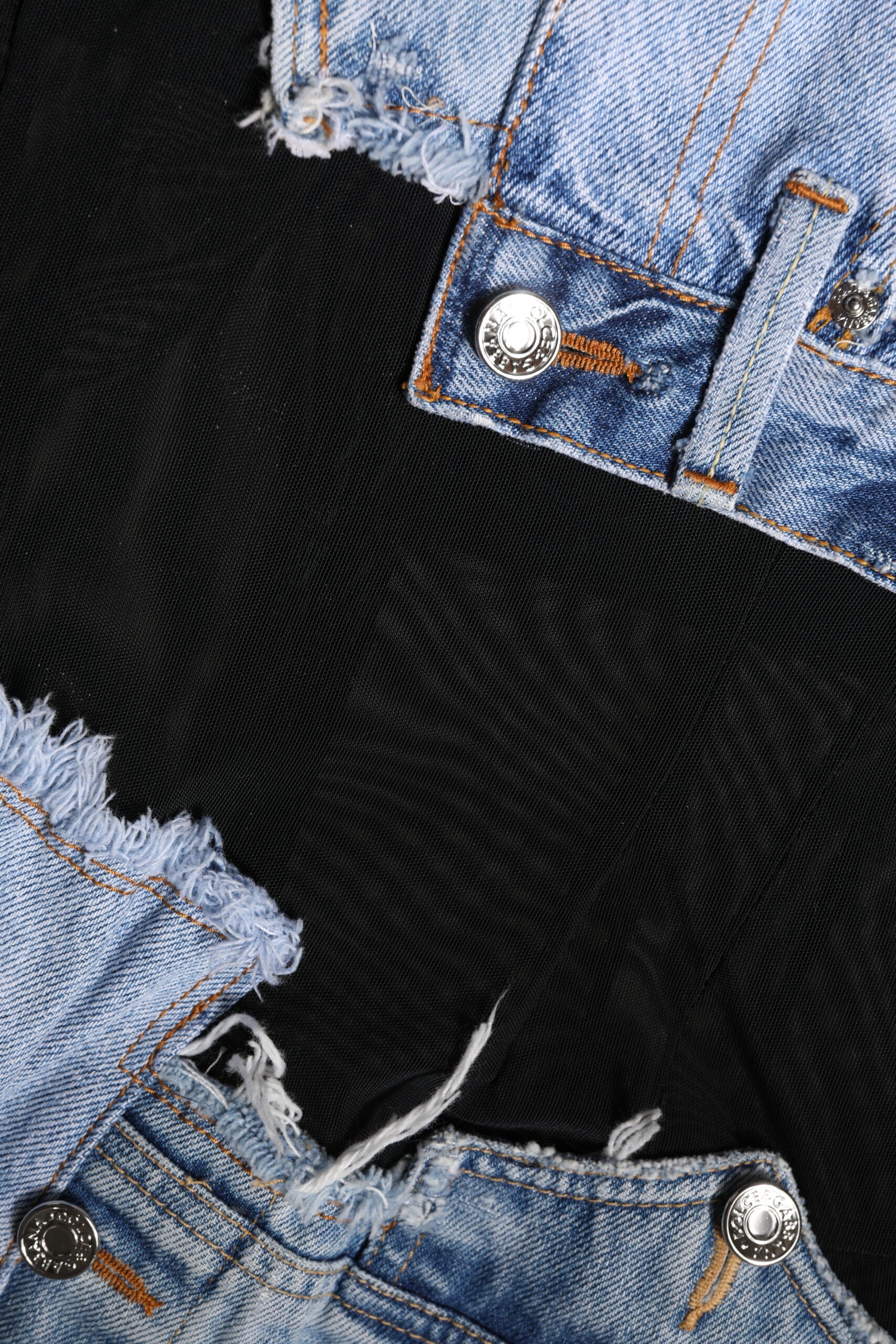 A pair of blue denim jeans with rips and tears on the knees, worn by a mannequin