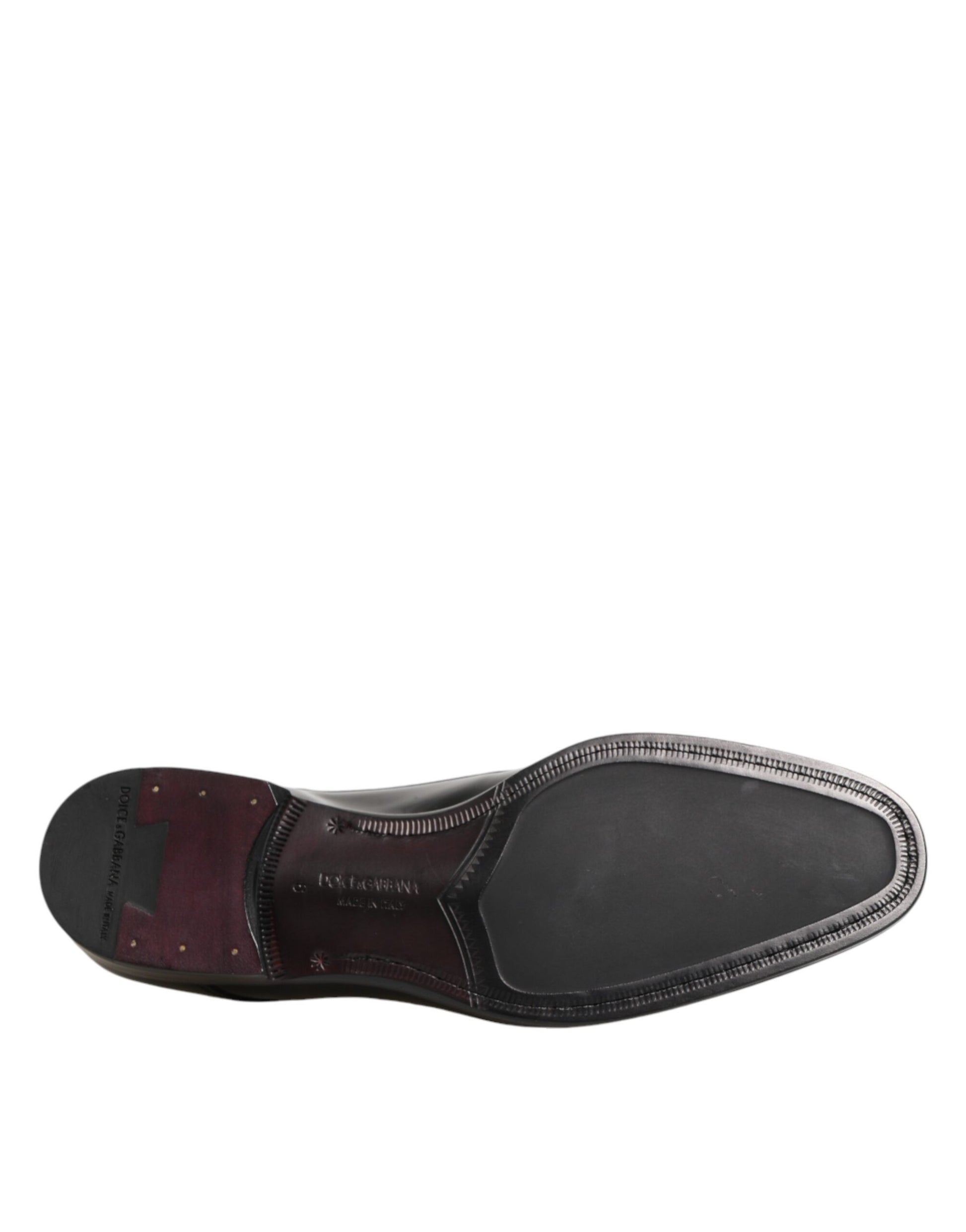 A single black leather dress shoe with a red accent on the toe cap and laces