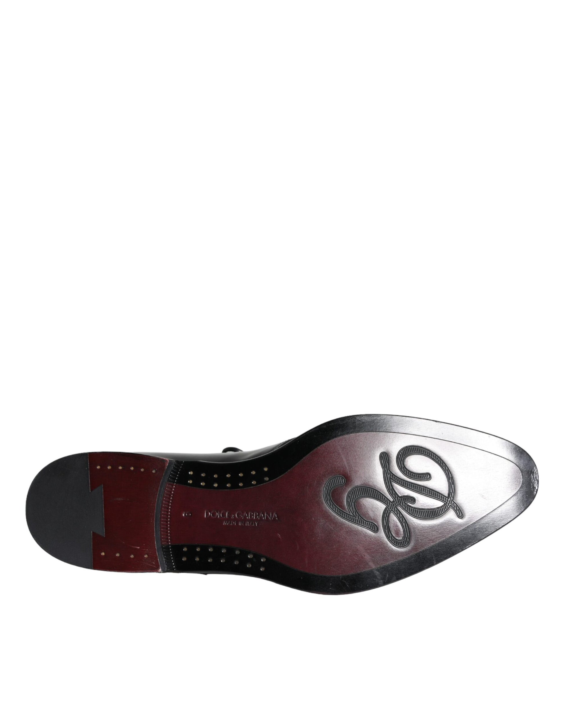 A single black leather shoe with a red sole, featuring the Dolce & Gabbana logo