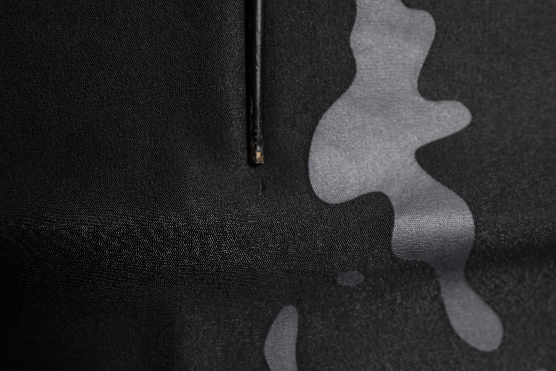 Black and white camouflage fabric with a zipper pull