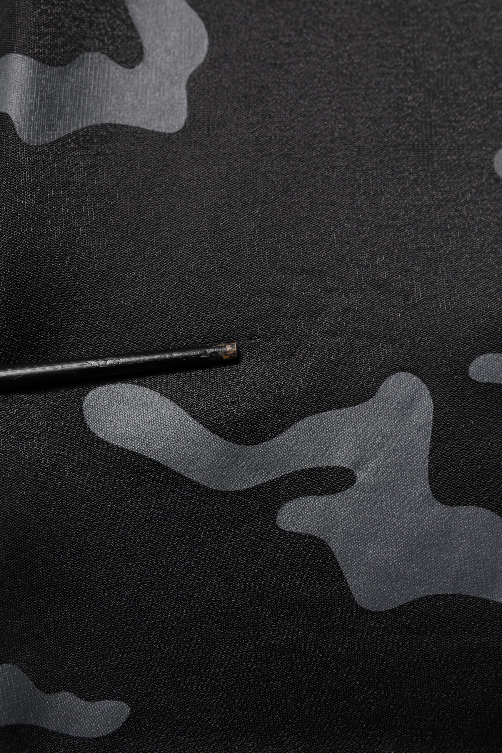 Camouflage fabric with a black thread stitched on it