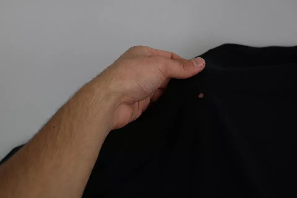 Hand holding black fabric with hole in front