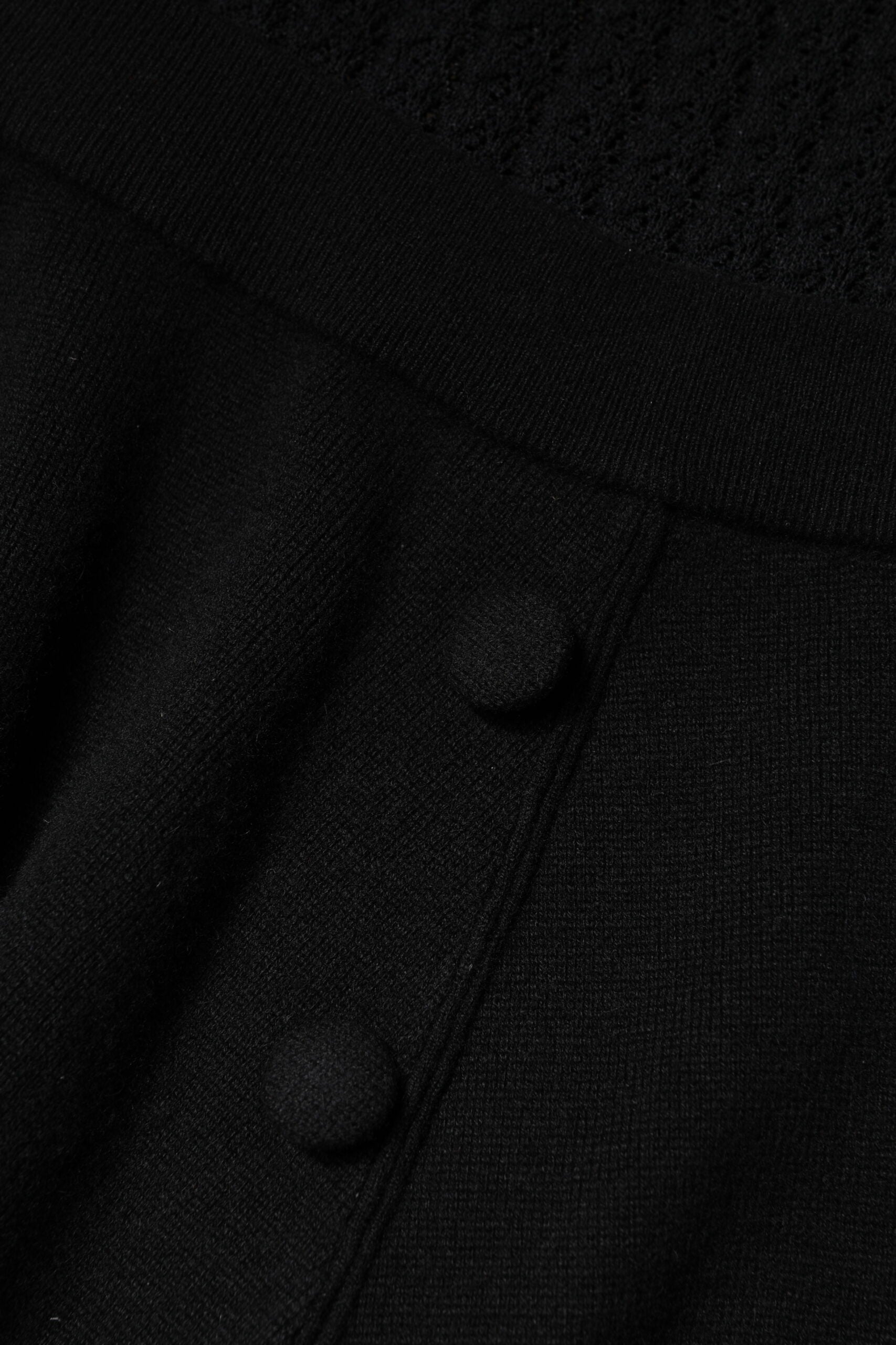 A black cashmere dress with long sleeves and a midi length. It features a buttoned front closure and is desig