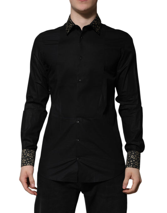 A black cotton dress shirt with long sleeves and gold accents. It is designed by Dolce & Gabbana, and it appe