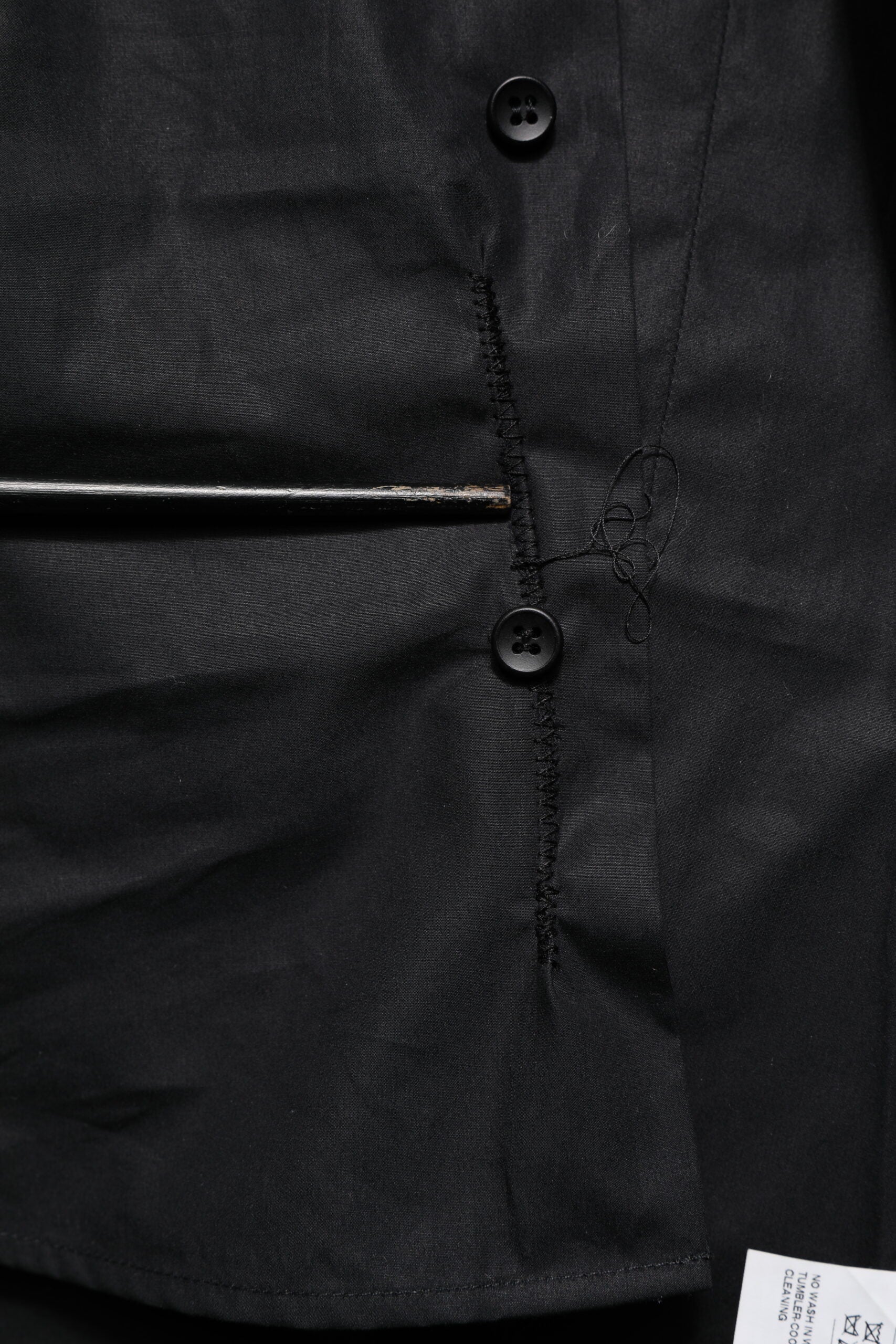 A black cotton dress shirt with long sleeves and gold buttons