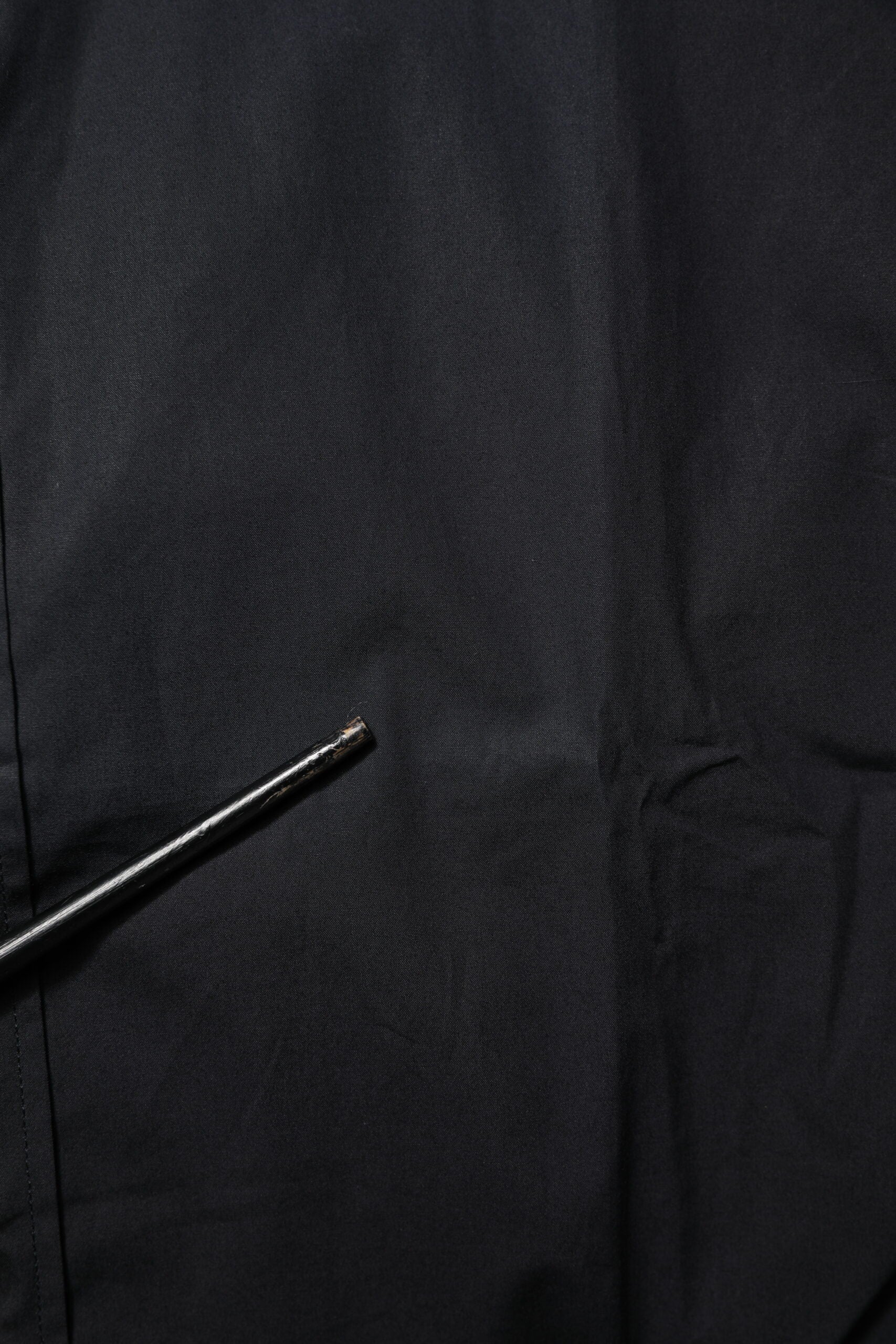 A black cotton dress shirt with long sleeves and a gold accent