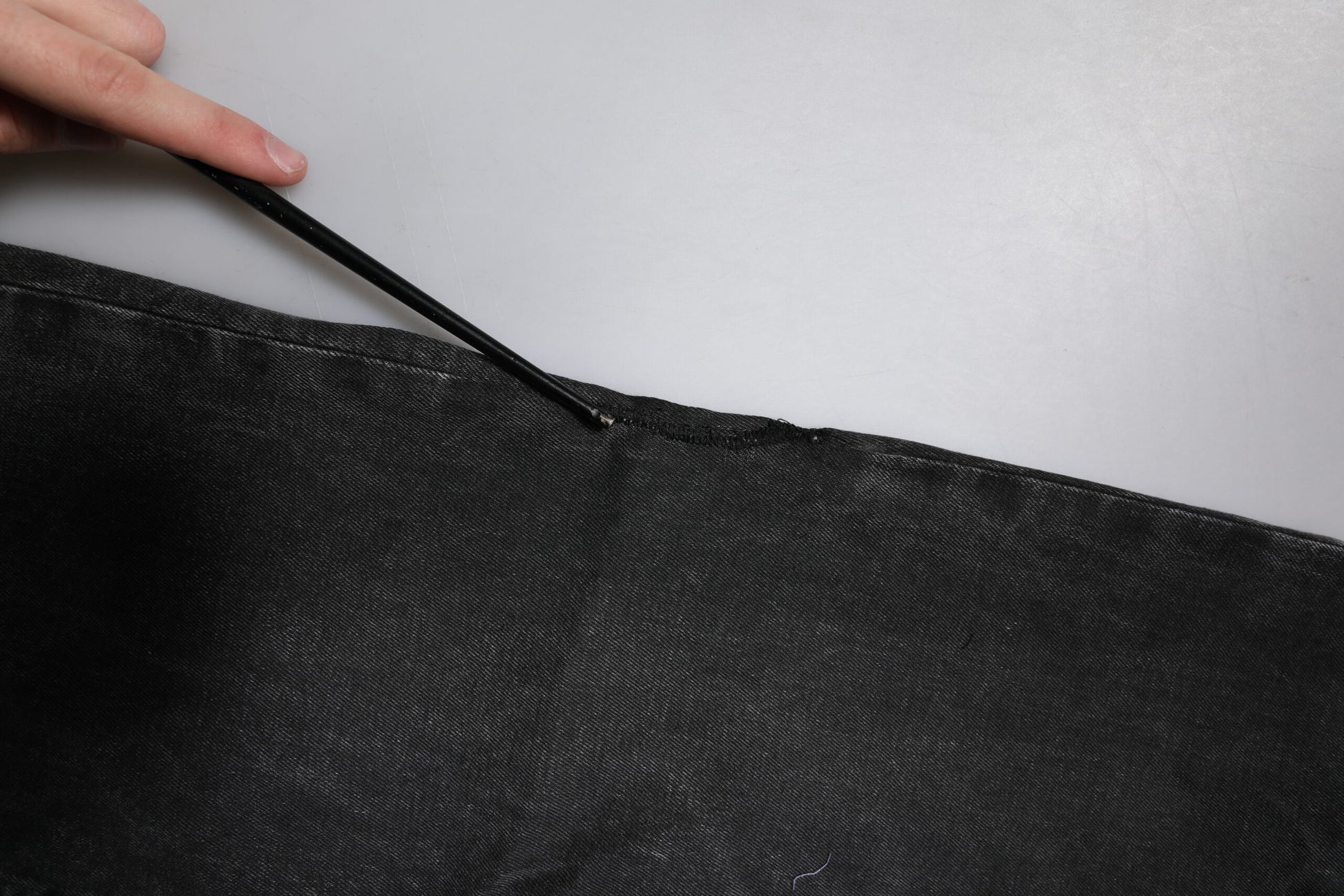 Hand holding a black fabric item on a table