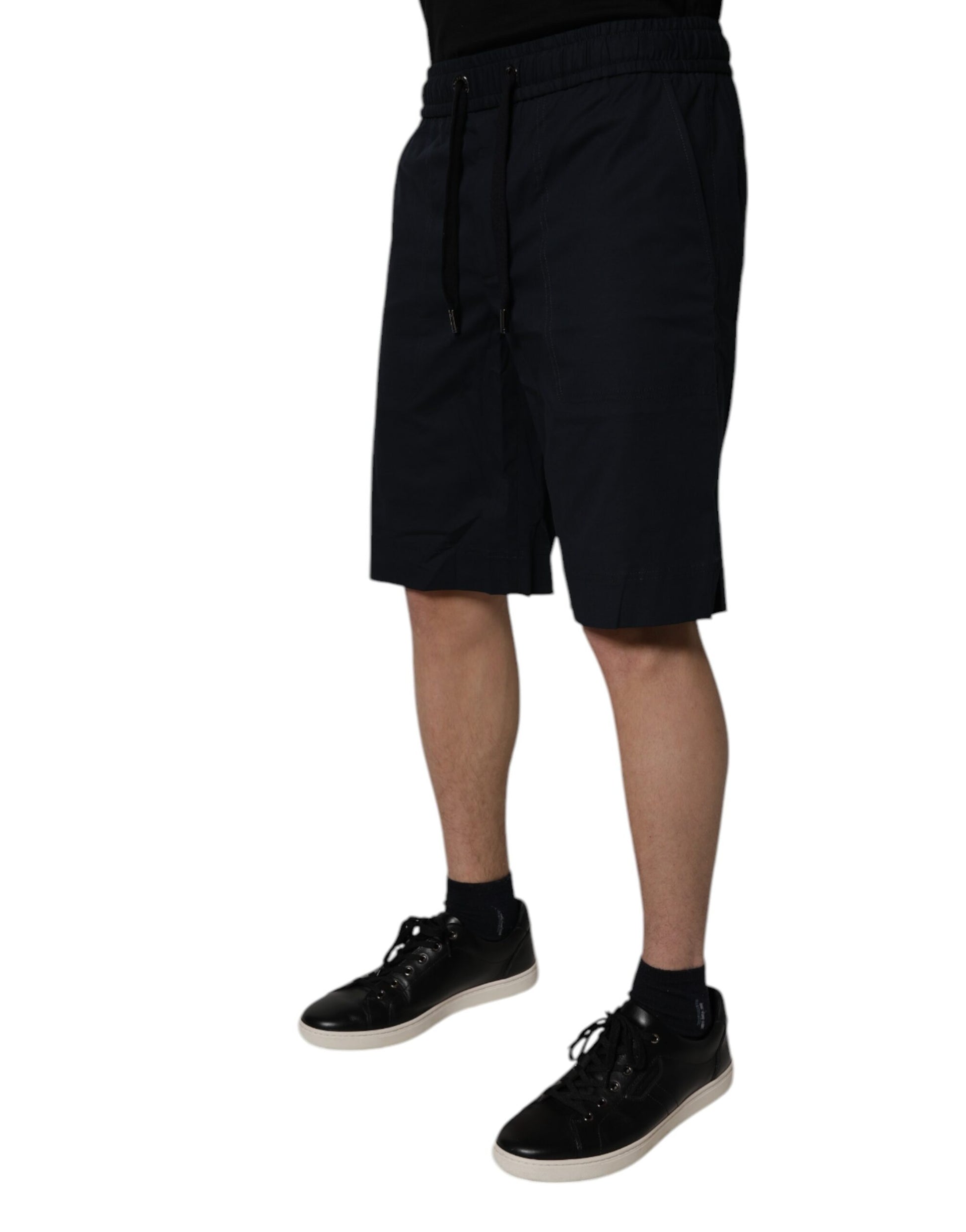 Man wearing black shorts and shoes standing against white background