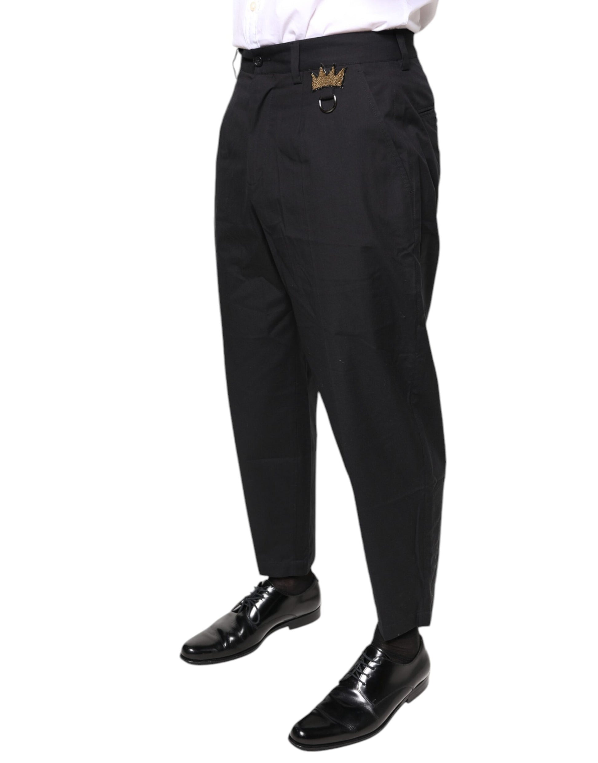 A pair of black dress pants with a gold crown emblem on the waistband