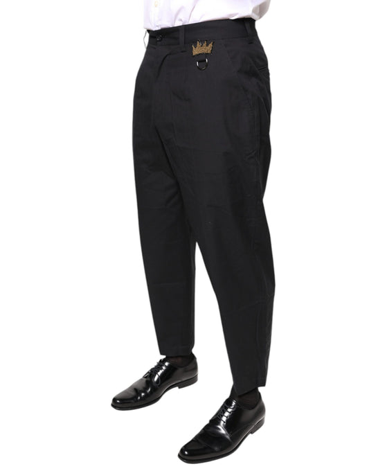 A pair of black dress pants with a gold crown emblem on the waistband
