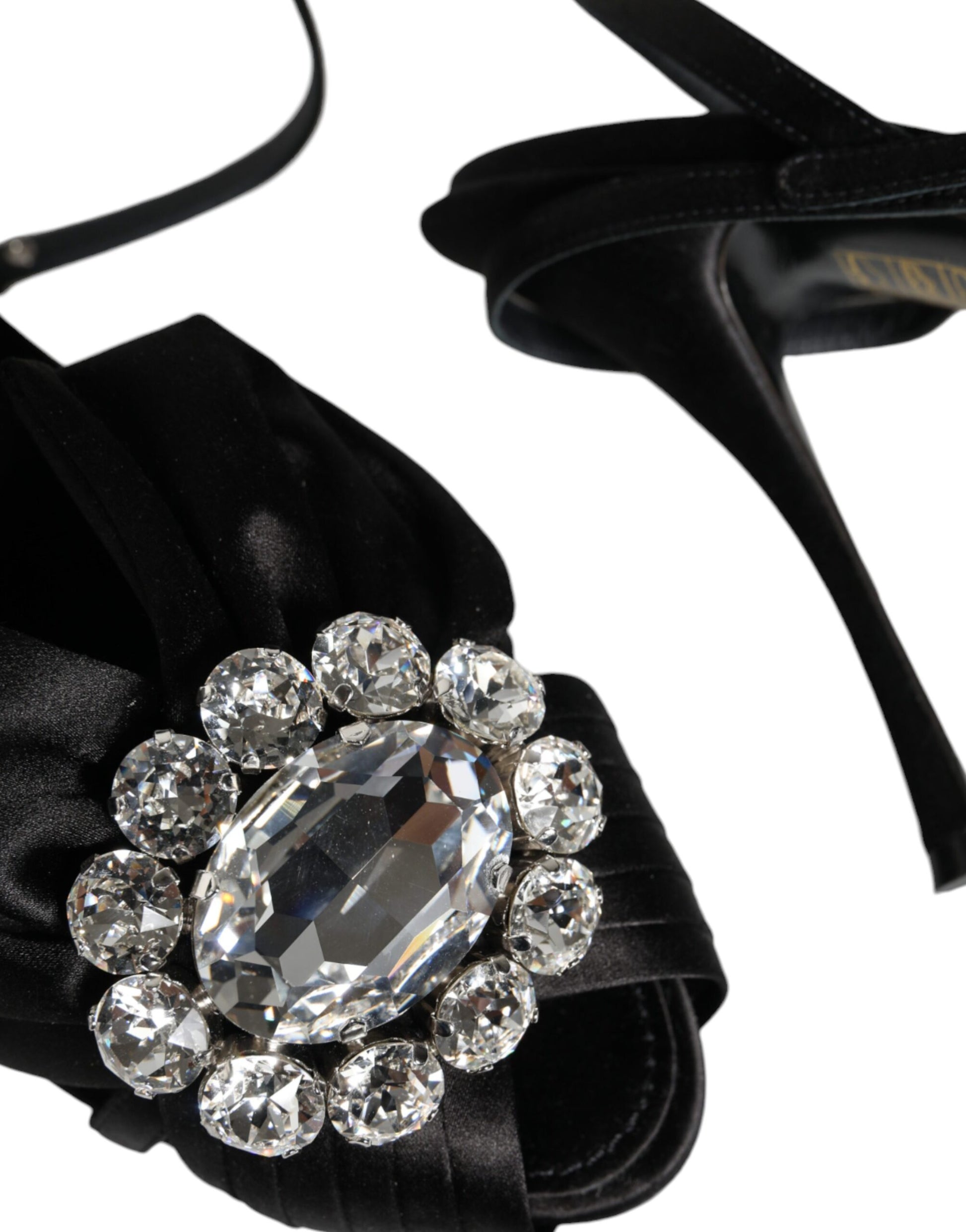 Black satin dress shoe with a large sparkling crystal brooch on its strap